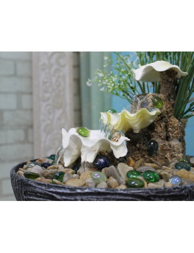 Dekoracyjna fontanna z naturalnymi muszlami i sztucznymi roślinami.